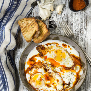 Eggs in garlicky yogurt - crispy fried egg whites and soft yolks, drizzled with butter paprika sauce, and served over a bed of cold, creamy garlicky yogurt - this is the ultimate egg dish to dig in with a piece of toasted bread! | www.viktoriastable.com
