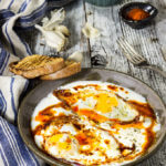 Eggs in garlicky yogurt - crispy fried egg whites and soft yolks, drizzled with butter paprika sauce, and served over a bed of cold, creamy garlicky yogurt - this is the ultimate egg dish to dig in with a piece of toasted bread! | www.viktoriastable.com