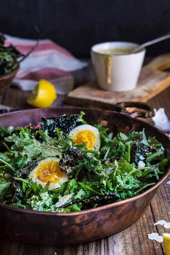 Kale salad with low fat Caesar dressing - baby kale and roasted kale chips, garlicky bread crumbs, and soft boiled eggs, drizzled with a healthy Caesar dressing which is packed with protein, low in fat, yet creamy and robust in flavor. | www.viktoriastable.com