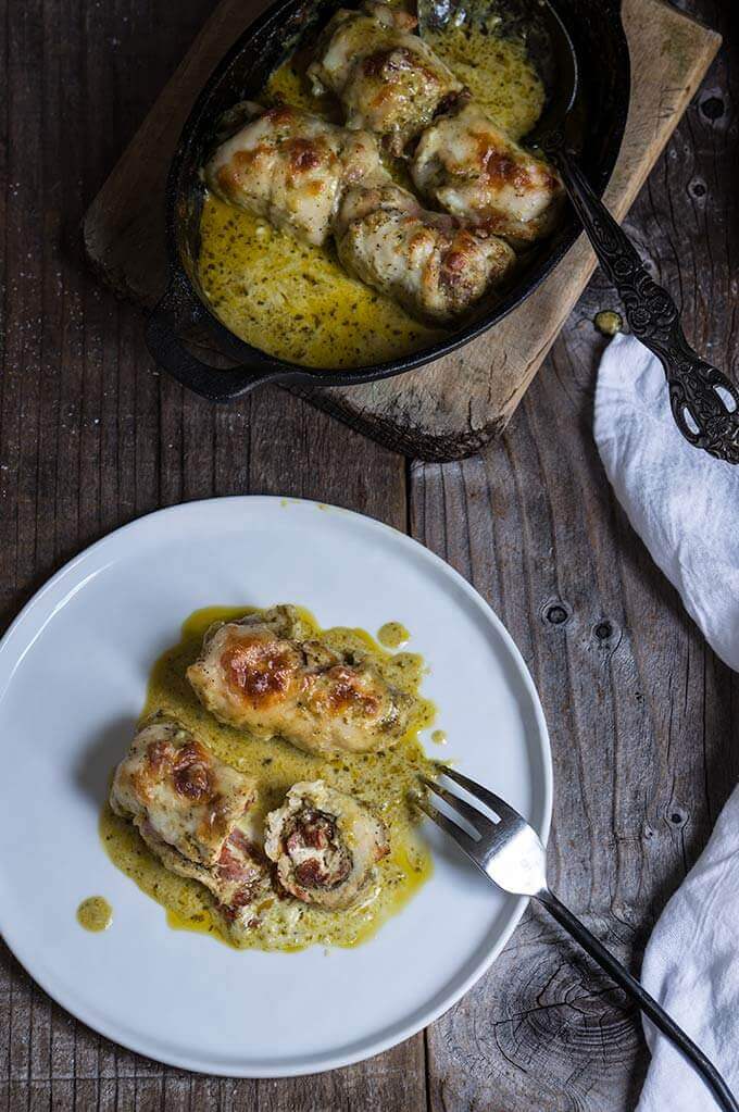 Stuffed chicken roll ups - delicious and easy to make, stuffed with pesto, prosciutto, sun-dried tomatoes and goat cheese, then smothered in creamy garlicky sauce, topped with mozzarella, and baked to perfection! | www.viktoriastable.com