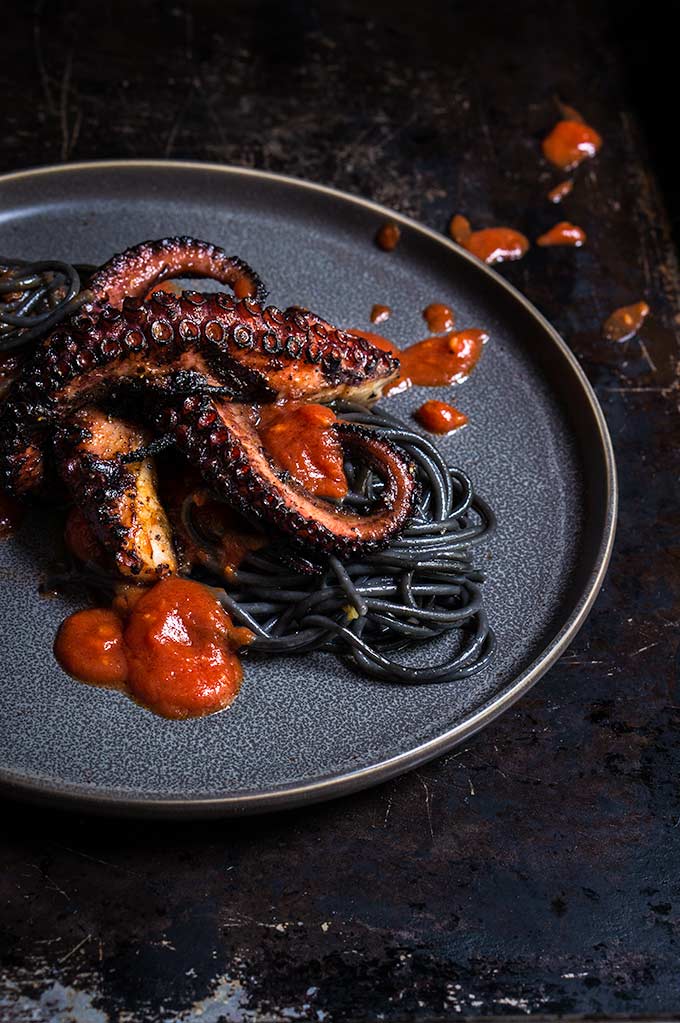 Grilled octopus over squid ink pasta and tomato garlic sauce | www.viktoriastable.com